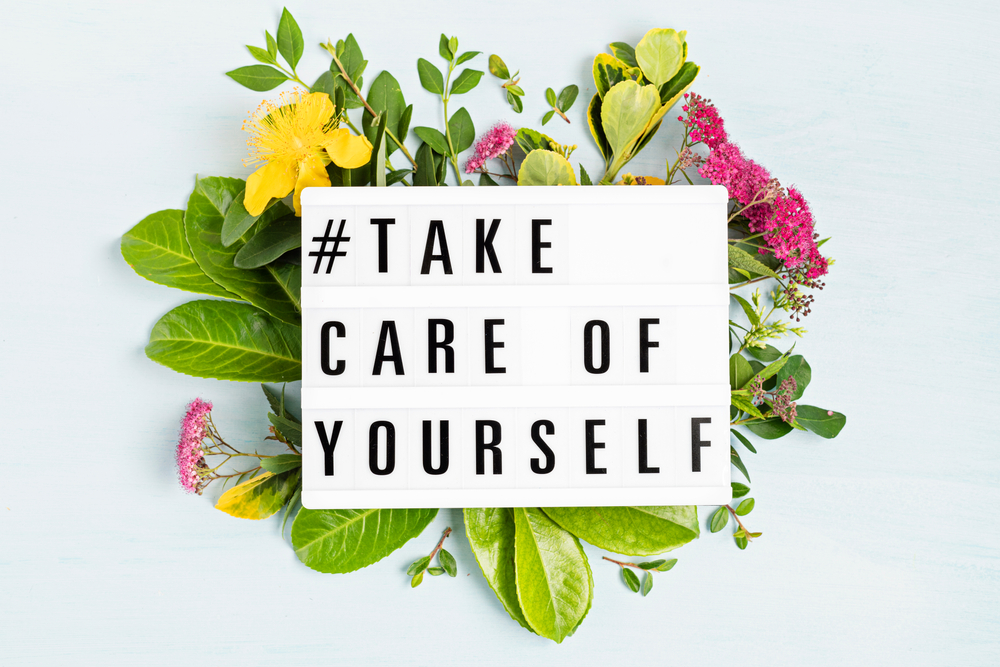 A sign with the saying "#take care of yourself" surrounded by lowers